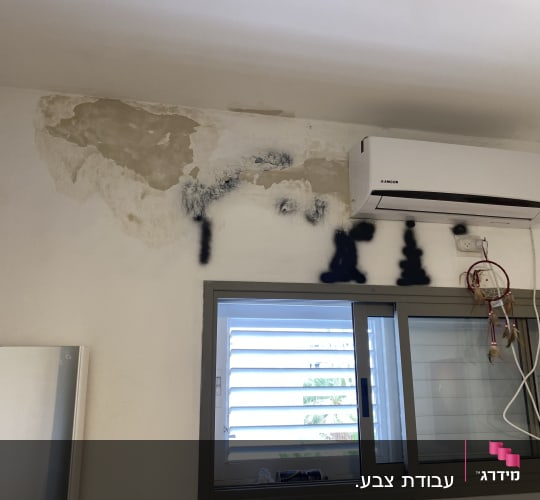 קיר עם כתמי צבע ותיקוני טיח ליד מזגן